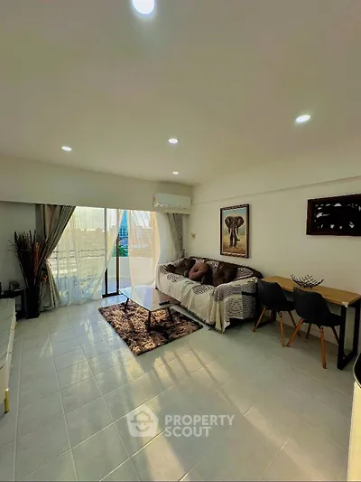 Spacious living room with modern decor and large windows offering natural light and balcony access.