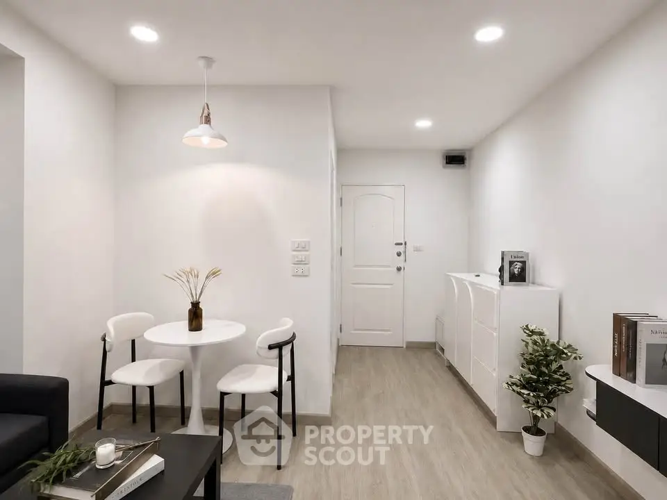 Modern minimalist living room with white walls, sleek furniture, and wooden flooring.