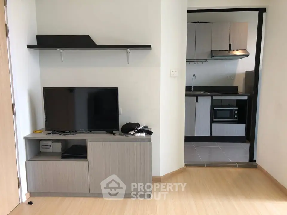 Modern living room with sleek TV stand and open kitchen layout in a stylish apartment.