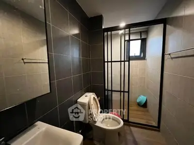 Modern bathroom with sleek dark tiles and glass partition