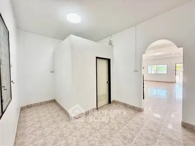 Spacious open-plan interior with tiled flooring and modern lighting, ideal for versatile living arrangements.