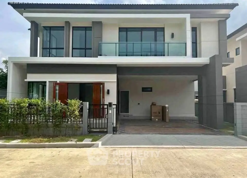 Modern two-story house with large windows and balcony in a suburban neighborhood.