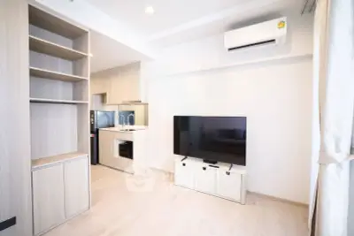 Modern living room with sleek TV setup and open kitchen layout in a stylish apartment.