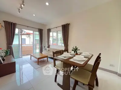 Charming living room with dining area and balcony access, featuring elegant decor and natural light.