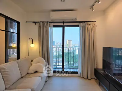 Modern living room with balcony view, cozy sofa, and sleek TV setup in urban apartment.