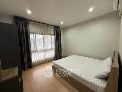 Spacious bedroom with large window and modern decor in a stylish apartment.