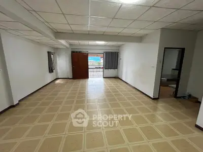 Spacious living room with tiled flooring and ample natural light, perfect for family gatherings.