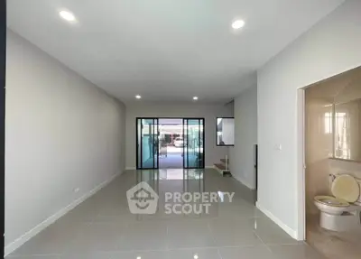 Spacious modern living room with glossy tile flooring and large sliding glass doors.