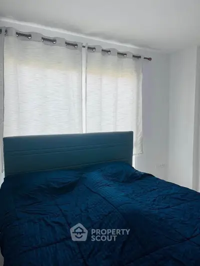 Cozy bedroom with modern blue bedding and natural light through large windows.