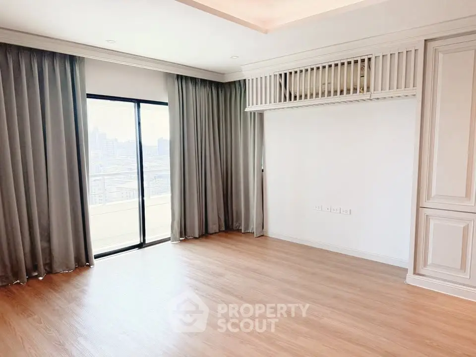 Spacious empty room with wooden flooring and large window offering city views, perfect for customization.
