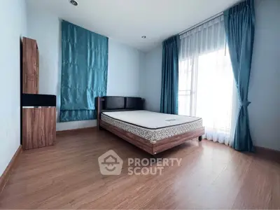 Spacious bedroom with wooden flooring and large window for natural light