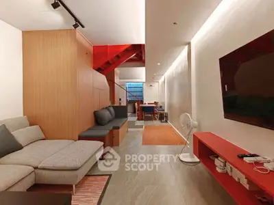 Modern living room with sleek design, featuring a cozy sofa, wall-mounted TV, and stylish lighting.