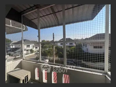 Charming balcony with protective netting and scenic neighborhood view, perfect for enjoying outdoor relaxation.