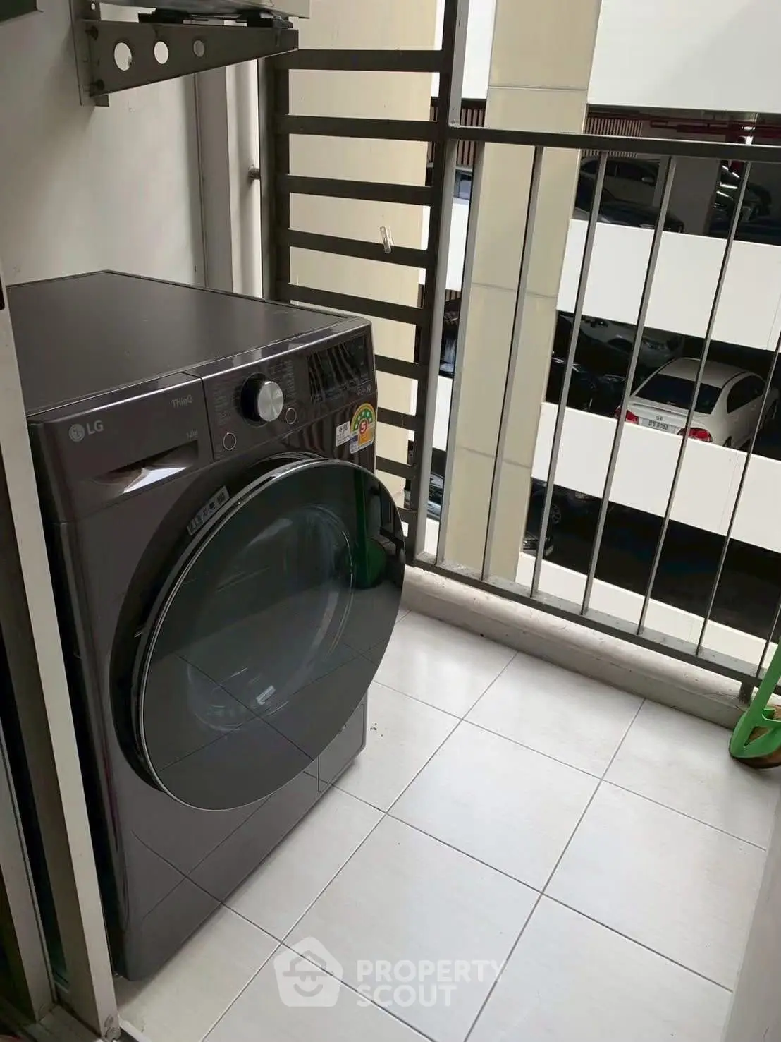 Compact balcony with modern washing machine in urban apartment setting.