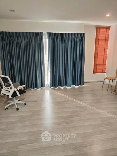 Spacious room with wooden flooring and large windows, perfect for a home office or study area.