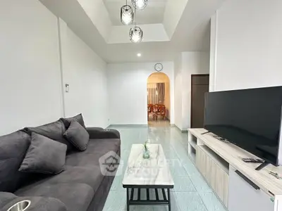 Spacious living room with modern decor and large TV, perfect for relaxation.