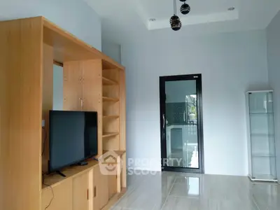 Modern living room with sleek wooden furniture and glass door leading to a bright outdoor space.
