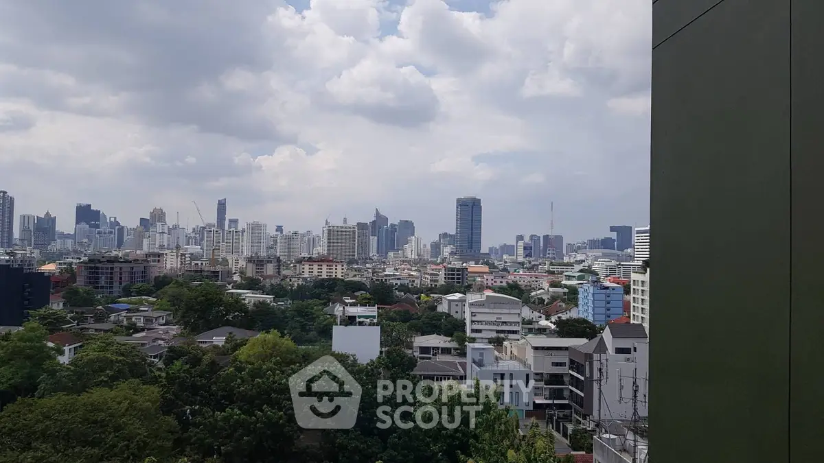 Stunning cityscape view from a high-rise building showcasing urban skyline and lush greenery.