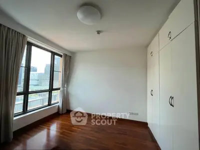 Spacious bedroom with city view and built-in wardrobe, featuring elegant wooden flooring and large windows.