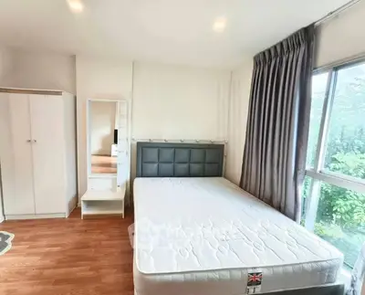 Spacious bedroom with large window and modern furnishings in a bright apartment.