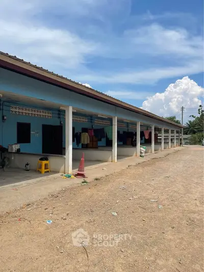 Single-story building with multiple units and outdoor laundry area under a clear blue sky.