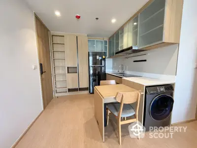 Modern kitchen with sleek cabinets, built-in appliances, and compact dining area in a stylish apartment.