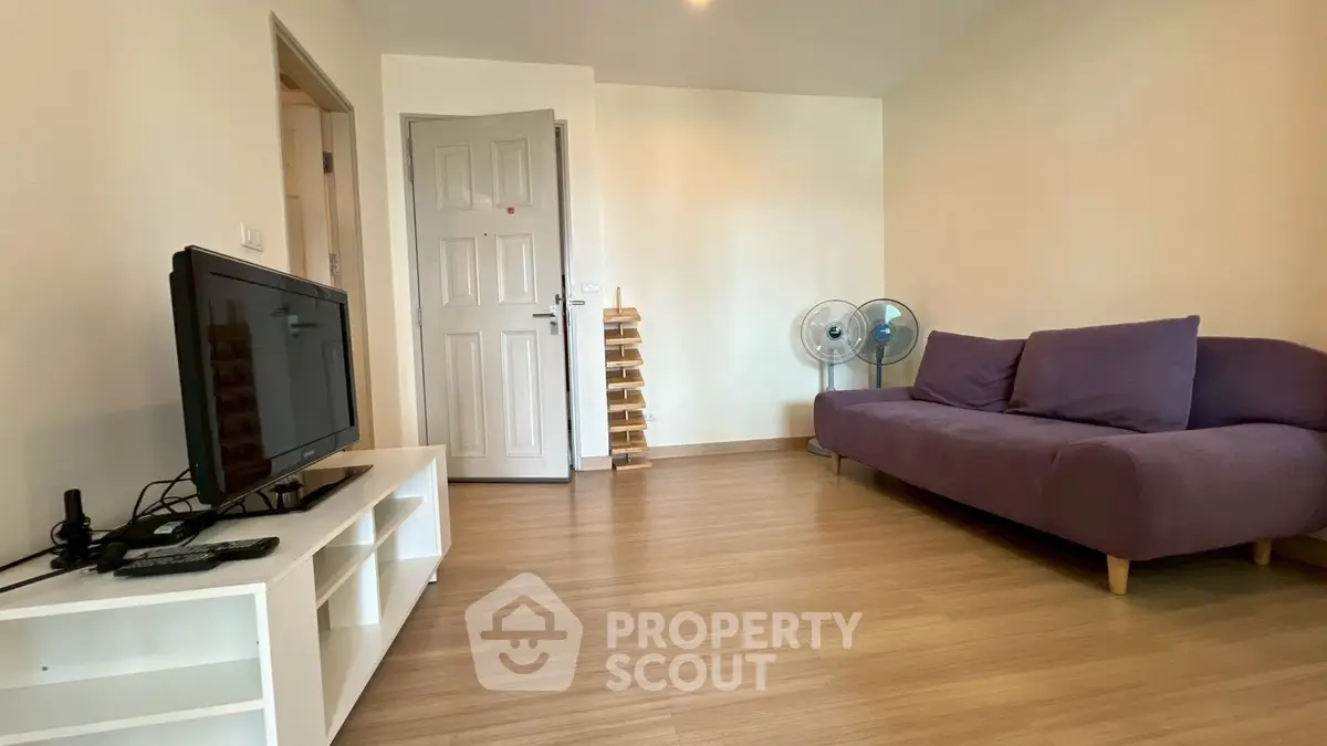 Spacious living room with modern decor and wooden flooring, featuring a cozy sofa and entertainment setup.