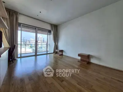 Spacious living room with wooden flooring and large balcony offering city views.