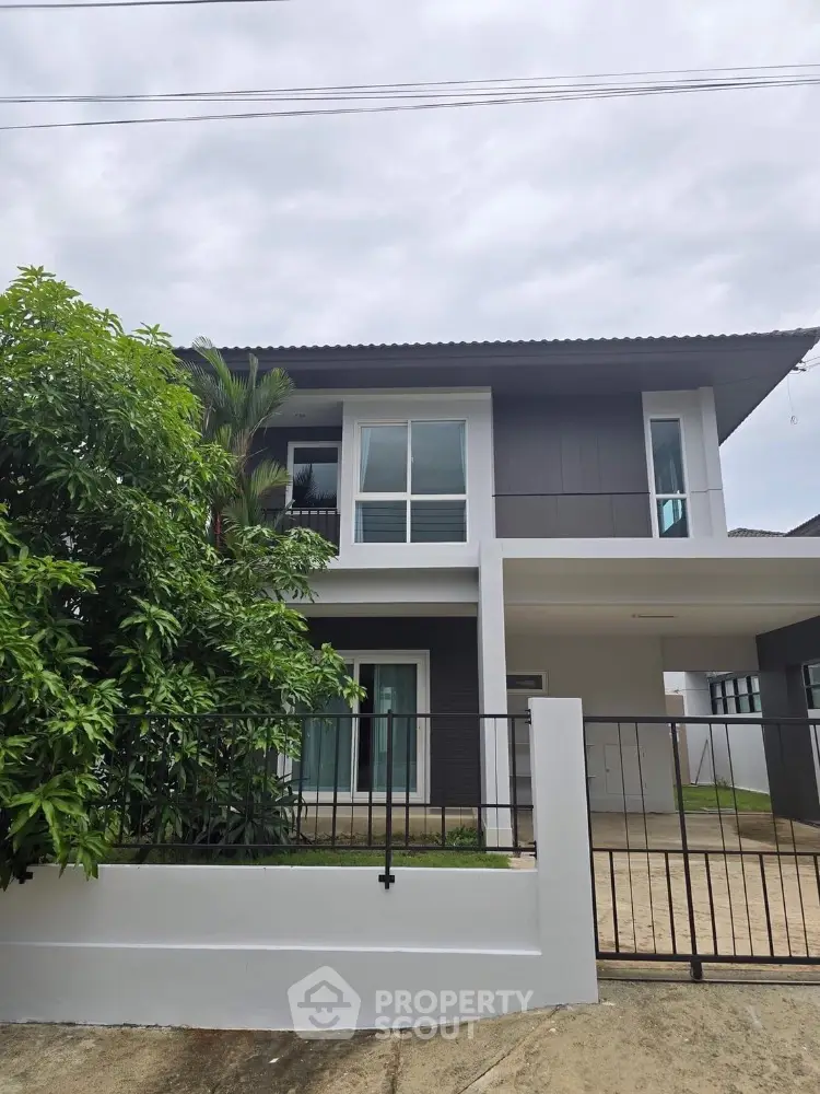 Modern two-story house with sleek design and lush greenery in a serene neighborhood.
