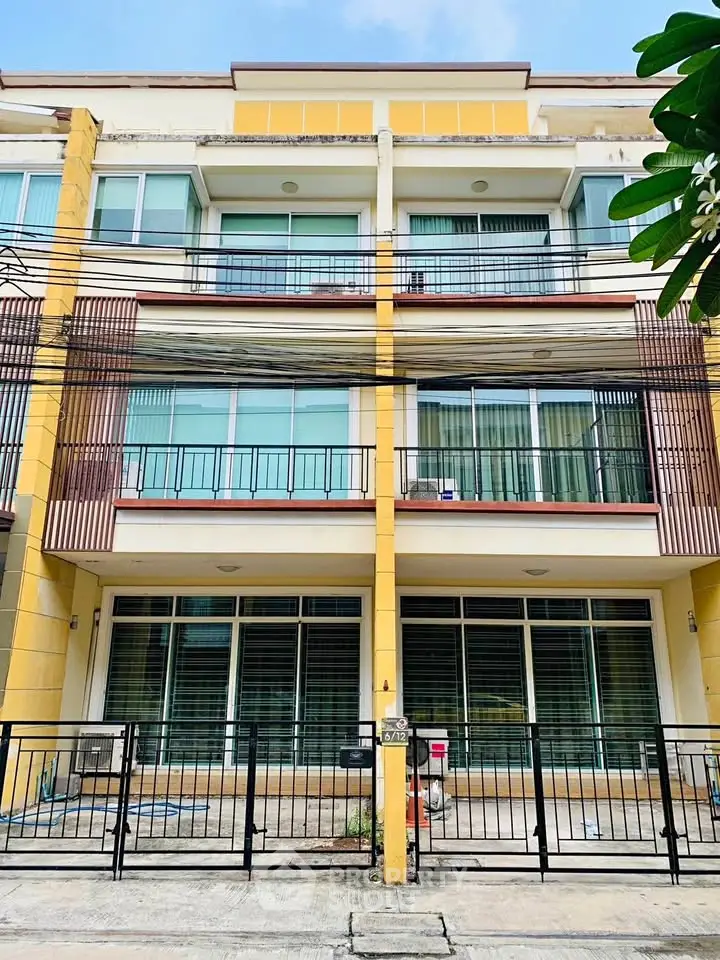 Modern multi-story townhouse with large windows and balconies in urban setting.