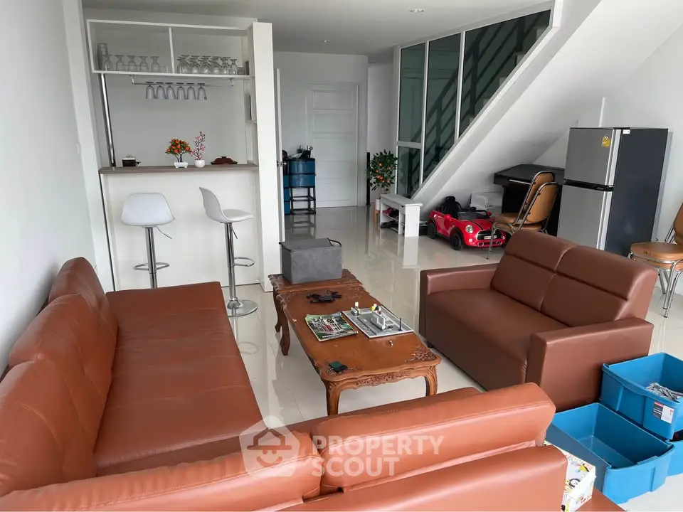 Spacious living room with modern furniture and open layout, featuring a stylish bar area and sleek design.