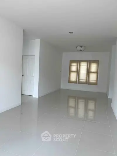 Spacious empty room with glossy tiled floor and large windows