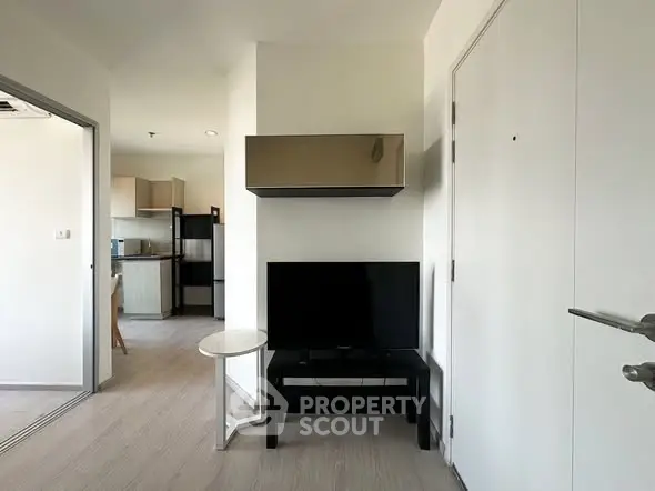 Modern apartment interior with sleek TV setup and open kitchen layout.