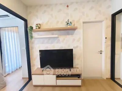 Modern living room with TV, stylish shelving, and wooden flooring in a cozy apartment.