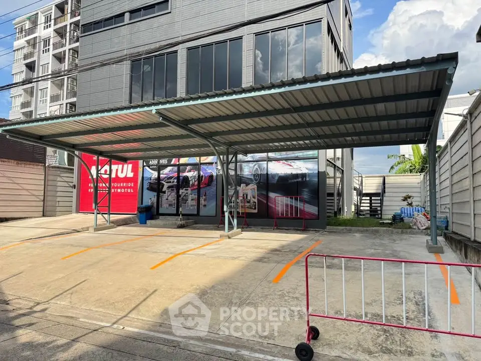 Modern commercial building with covered parking area and vibrant signage, ideal for business opportunities.
