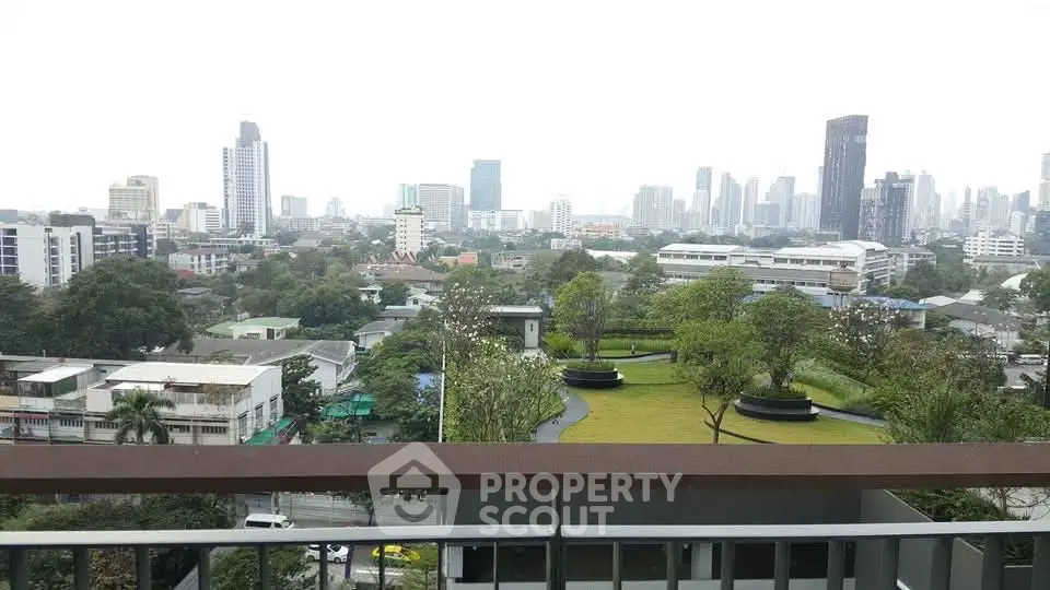 Stunning cityscape view from a high-rise balcony overlooking lush greenery and urban skyline.