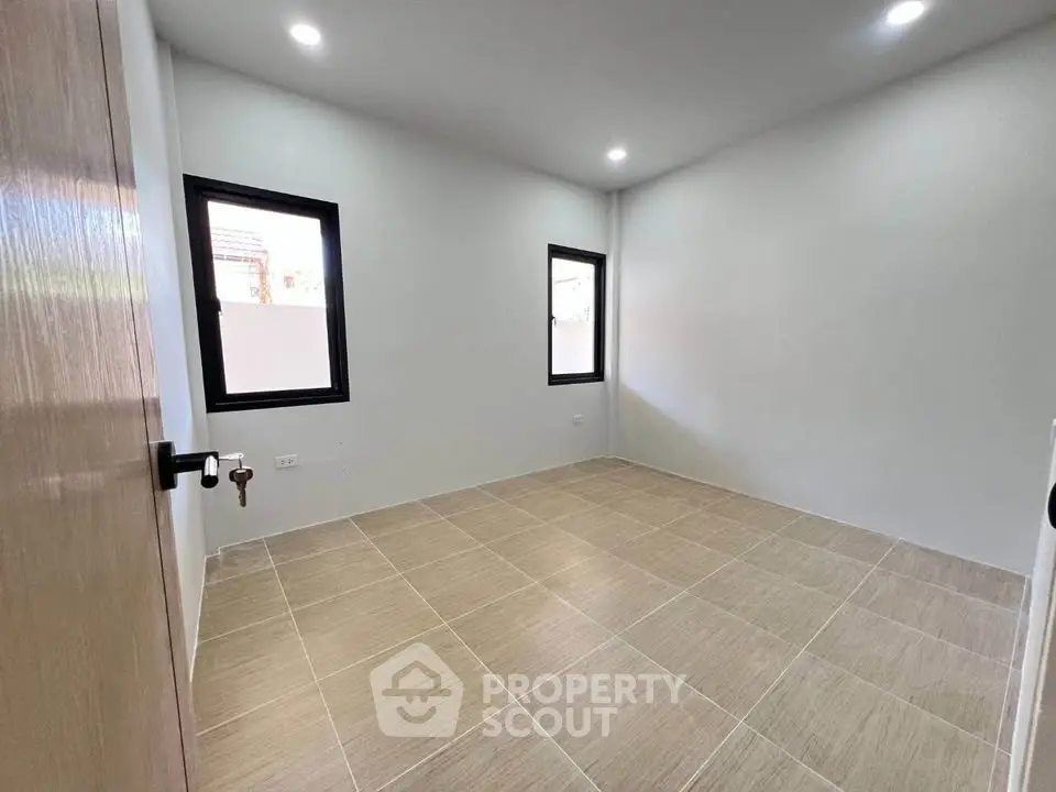 Spacious unfurnished room with tiled flooring and two windows, perfect for customization.
