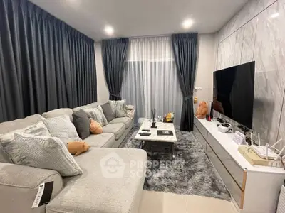 Luxurious living room with plush gray sofa, modern decor, and large flat-screen TV, perfect for relaxation.