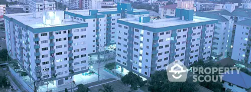 Twilight view of a modern residential apartment complex with ample lighting and a serene urban backdrop, ideal for city dwellers seeking a blend of comfort and convenience.