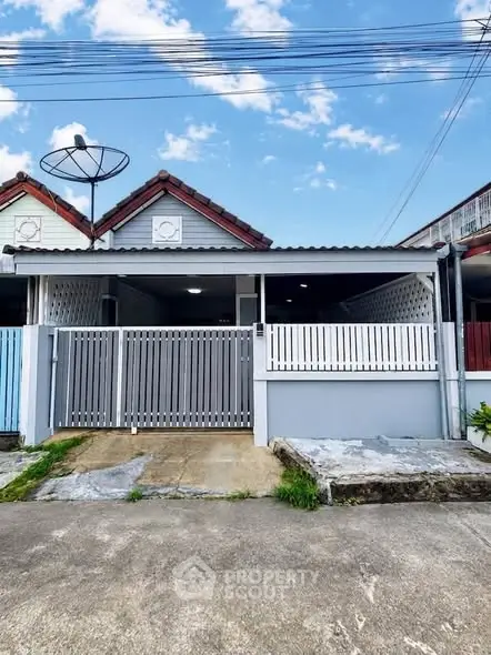 Charming single-story house with gated entrance and satellite dish, perfect for cozy living.