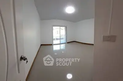 Spacious empty room with glossy tiled floors and sliding glass doors leading to balcony.