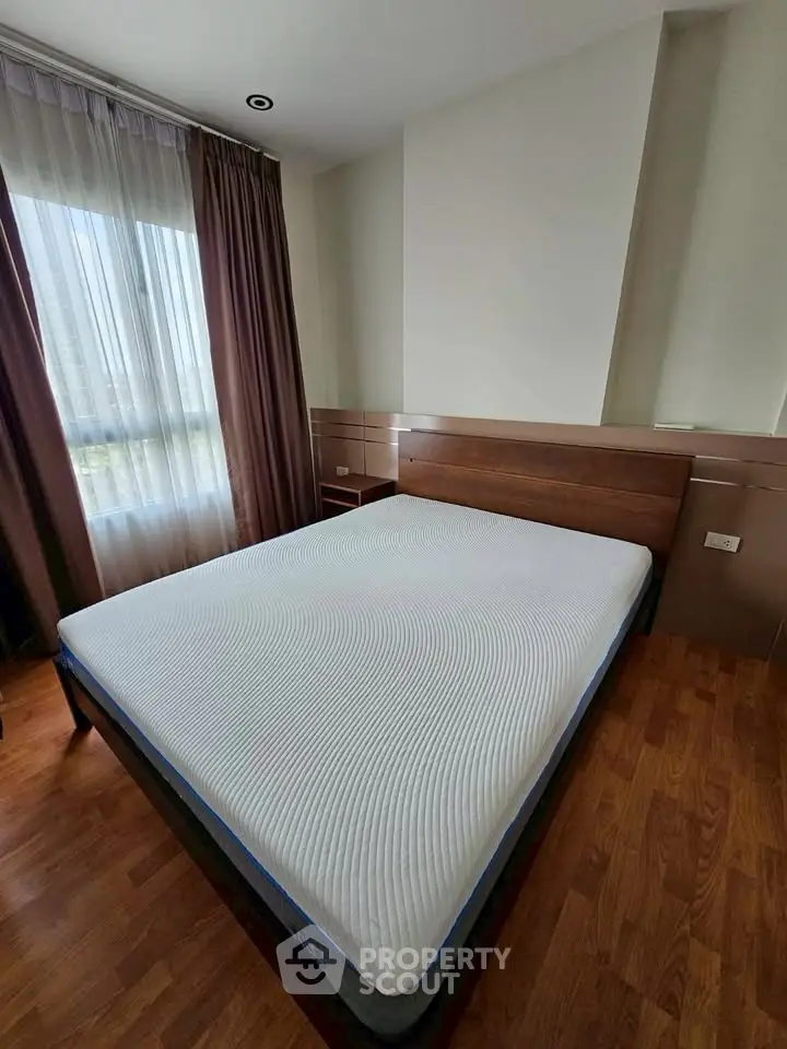 Spacious bedroom with large window and modern wooden flooring