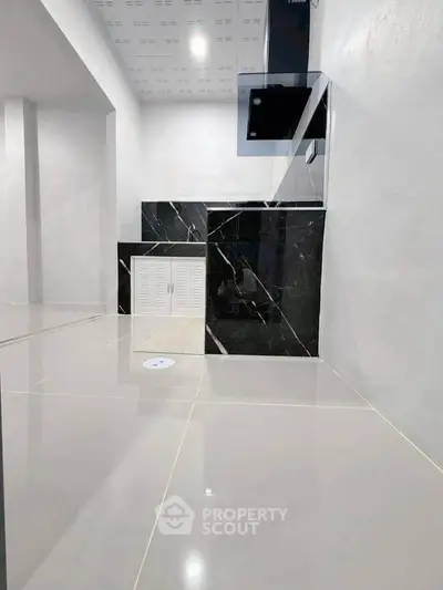 Modern minimalist kitchen with sleek black and white design, glossy tiles, and open layout.