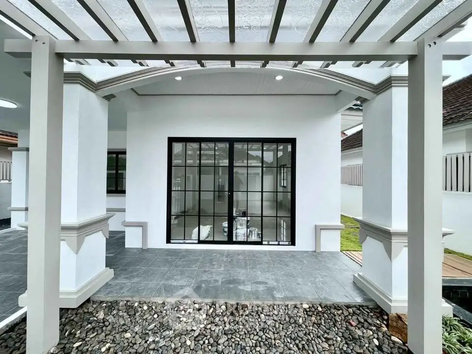 Modern home exterior with stylish pergola and sleek black-framed windows.