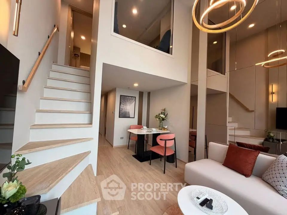 Modern duplex living room with stylish decor and open layout, featuring elegant staircase and cozy seating area.