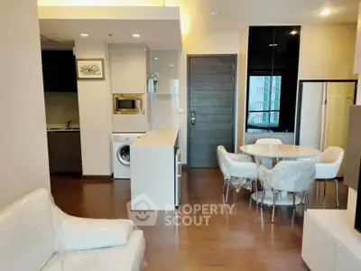 Modern open-plan living room with kitchen and dining area, featuring sleek appliances and stylish furniture.