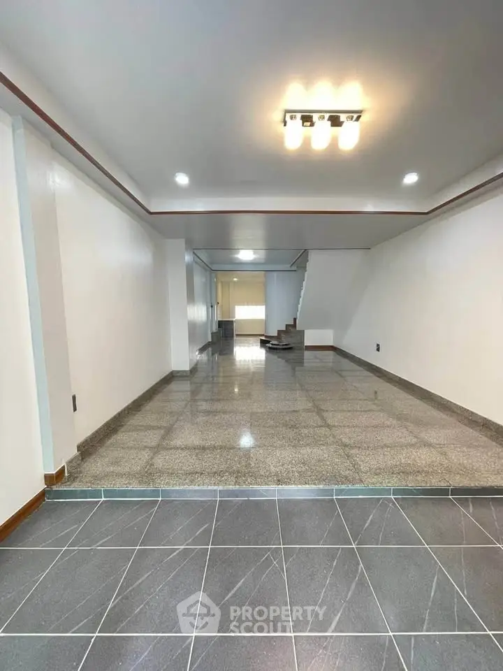 Spacious open-plan living area with modern lighting and tiled flooring, perfect for customization.