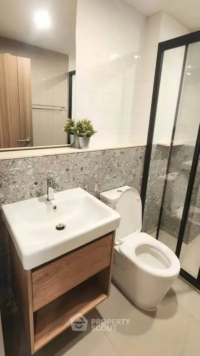 Modern bathroom with sleek design, featuring a stylish sink and toilet, complemented by a glass shower enclosure.