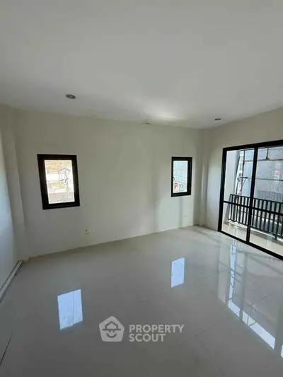 Spacious empty room with large windows and balcony access, ideal for customization.
