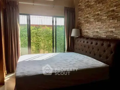 Cozy bedroom with large window and stylish stone accent wall